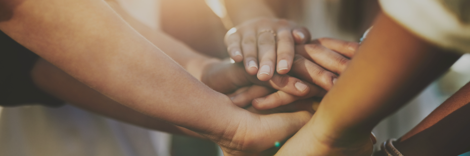 Multiple hands stacked on top of each other in a team huddle